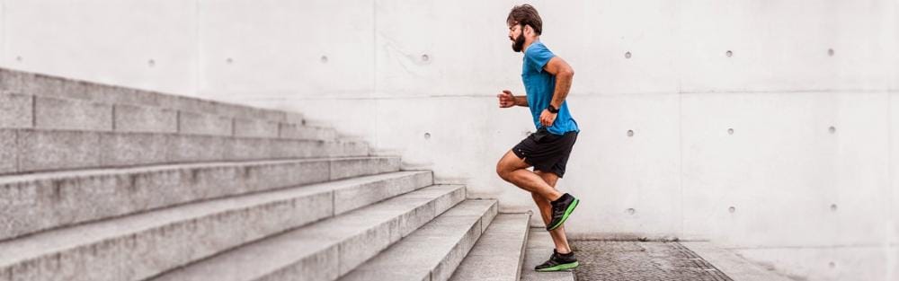 Sporty man running up steps in urban setting