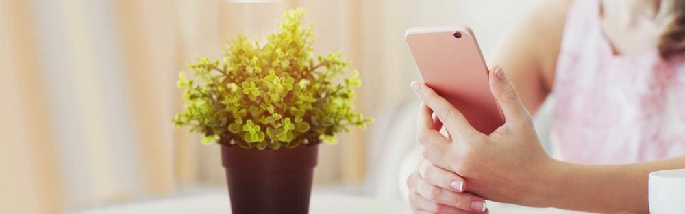 Woman in summer cafe holding a pink phone