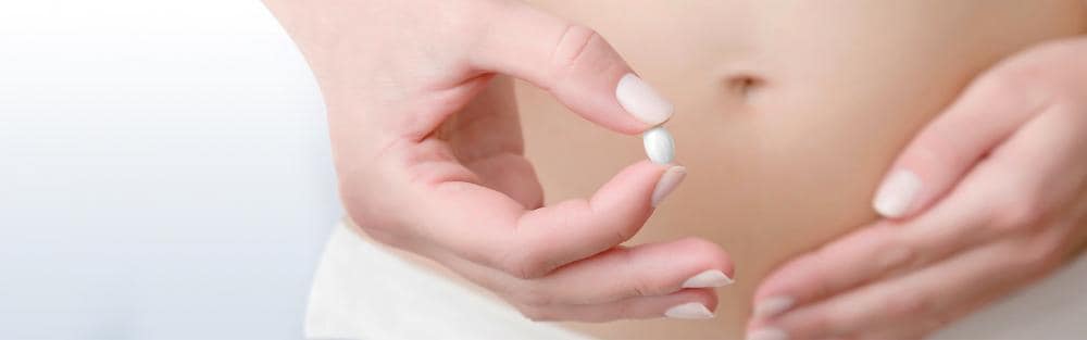 Young woman's hand holding pill
