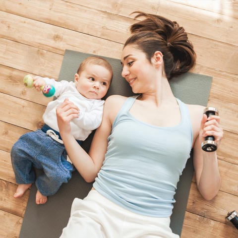 Majka i beba dečak leže na podu i vežbaju